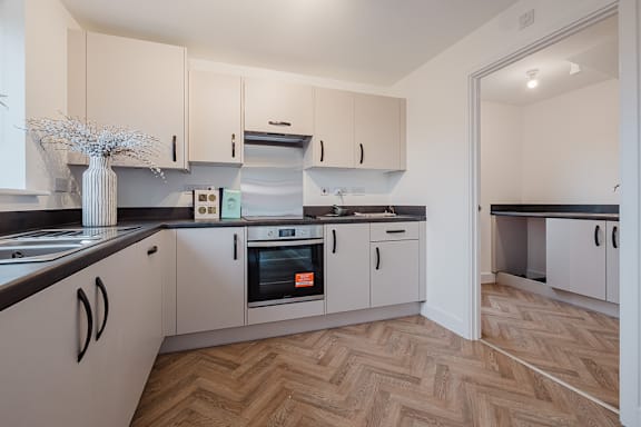 A kitchen with white cabinets and a wooden floor.
