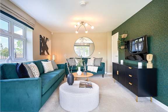 A living room with a green couch, a white coffee table, and a television.