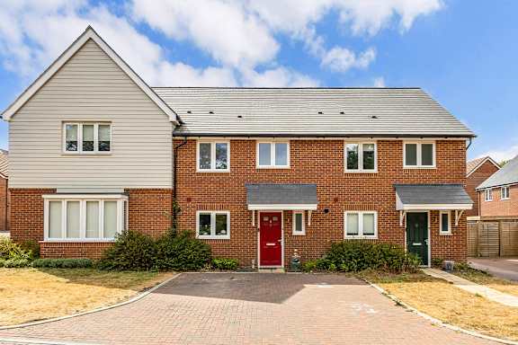 A red brick house with a grey roof and a grey front door.