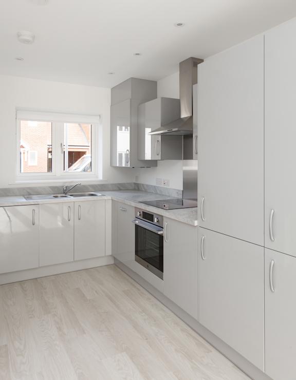 A modern kitchen with white cabinets and a wooden floor.