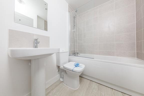 A white toilet with a blue flower on the lid sits next to a white sink in a bathroom.