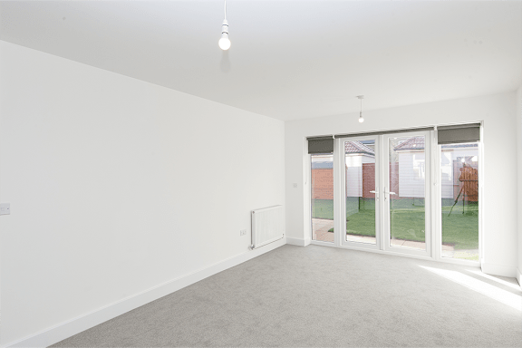 A white room with a sliding glass door leading to a backyard.
