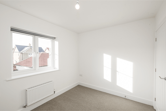 A white room with a window and a radiator.