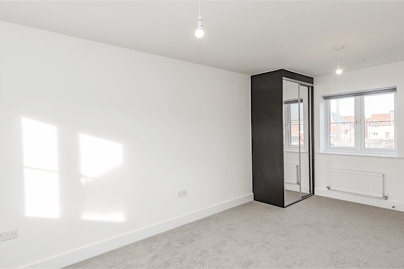 A room with a white wall and a black wardrobe.