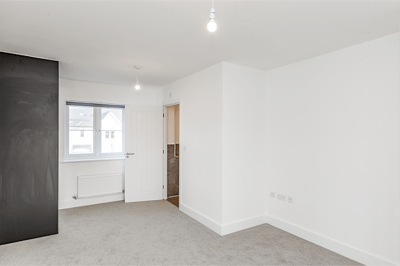 A room with a grey carpet and white walls.