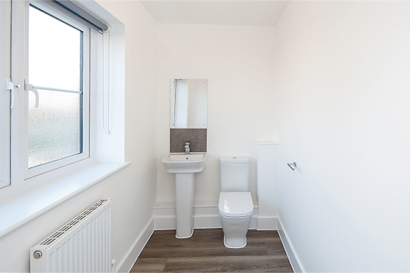 A white bathroom with a toilet, sink, and mirror.