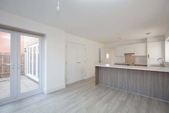 A modern kitchen with a white countertop and wooden flooring.