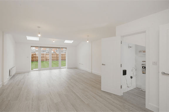 A spacious room with white walls and a wooden floor.