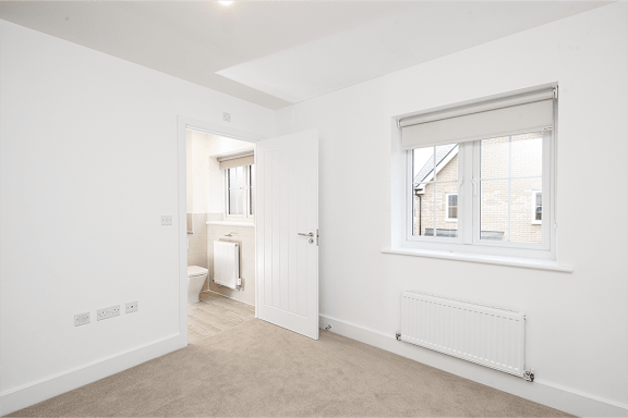 A white room with a toilet, a window, and a radiator.