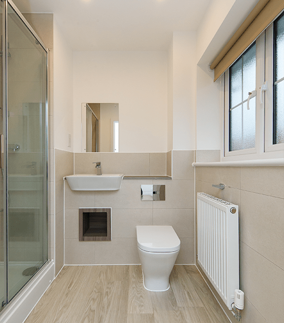 A white toilet sits in a bathroom next to a sink and a window.