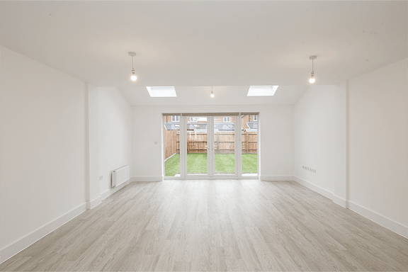 A large empty room with wooden floors and white walls.