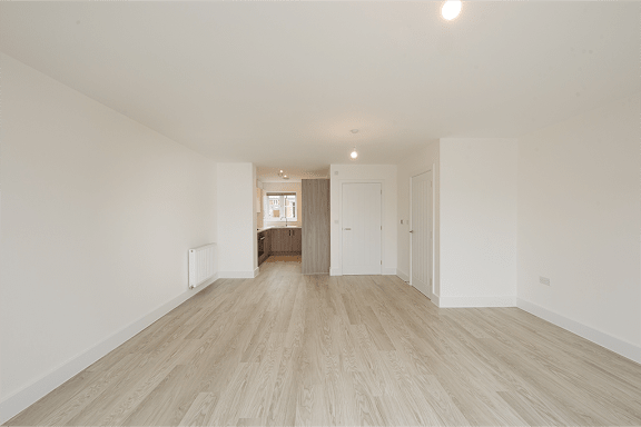 A long empty room with wooden floors and white walls.