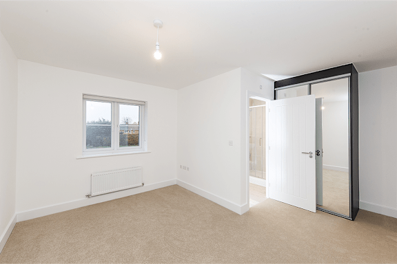 A room with a window, a door, and a radiator.