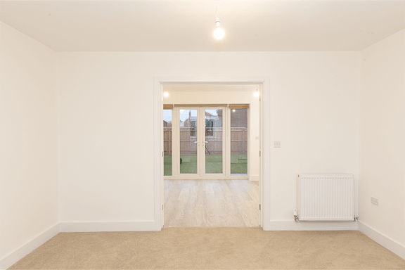 A room with a white wall and a window with a view of a backyard.