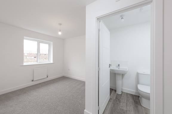 A white bathroom with a toilet, sink, and window.