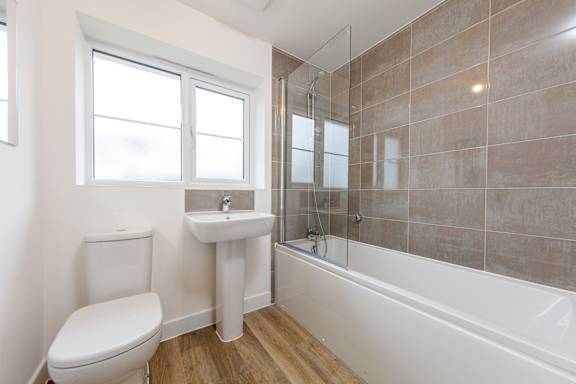 A white toilet sits next to a sink in a tiled bathroom.