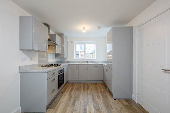 A kitchen with white cabinets and a wooden floor.