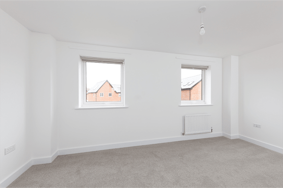 A room with two windows and a radiator on the wall.