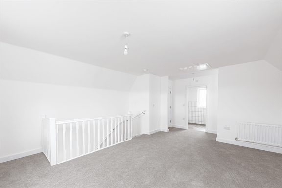 A spacious, empty room with white walls and carpeted floor.
