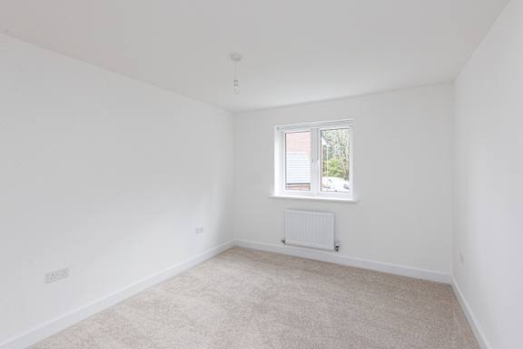 A white room with a window and a radiator on the floor.