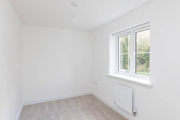 A white room with a window and a radiator on the wall.
