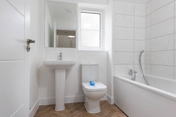 A white bathroom with a toilet, sink, and bathtub.