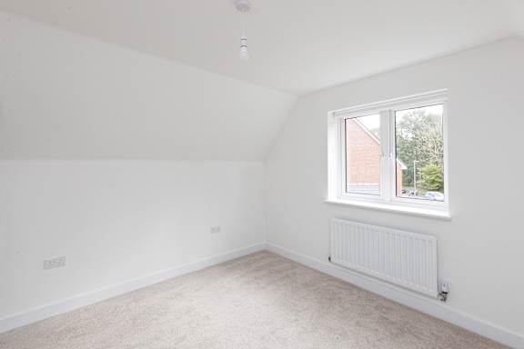 A white room with a window and a radiator on the wall.