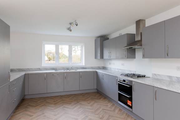 A kitchen with grey cabinets and a wooden floor.
