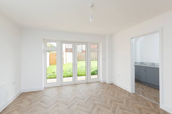 A room with a herringbone parquet floor and a sliding door.