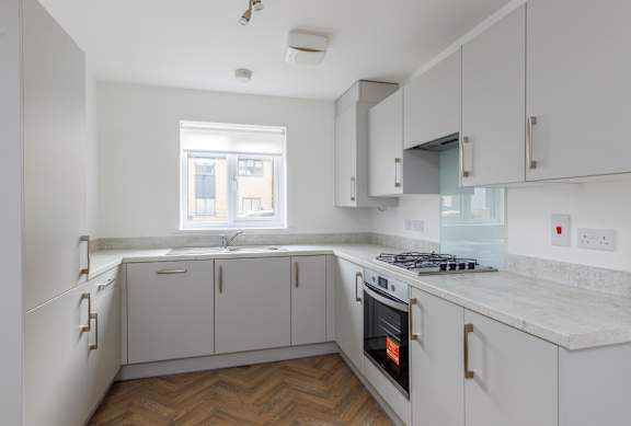 A kitchen with a stove, cabinets, and a window.