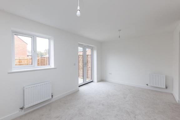 A white room with a carpeted floor and a window.