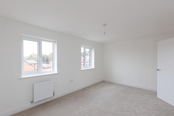 A room with a white ceiling, two windows, and a radiator on the floor.
