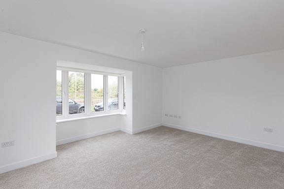 A large empty room with a window overlooking a parking lot.