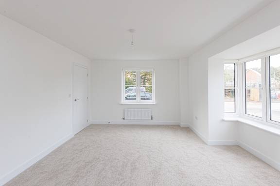 A large empty room with a window overlooking a street.