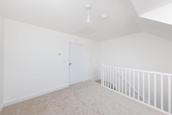 A white room with a carpeted floor and a white door.