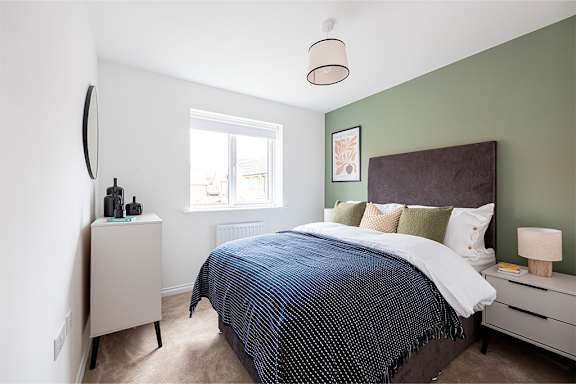 A bedroom with a bed, nightstand, and window.