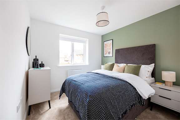 A bedroom with a bed, nightstand, and window.