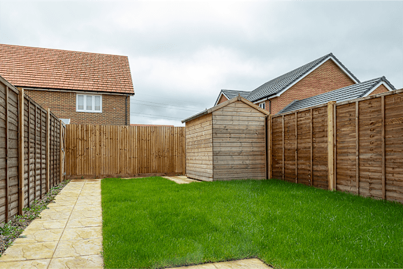 A backyard with a wooden fence and a green lawn.