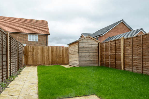a garden with a wooden fence and a lawn