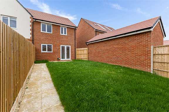 A backyard with a wooden fence and a brick house.