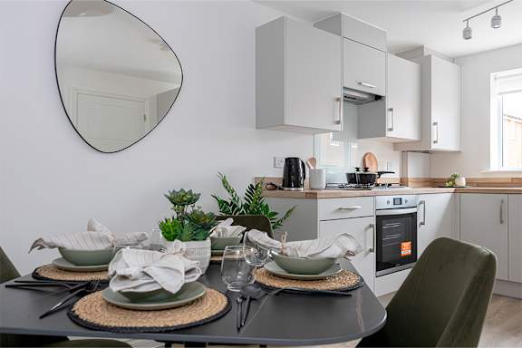 A modern kitchen with a dining table set for two.