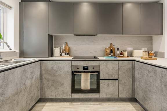 A modern kitchen with a marble countertop and stainless steel appliances.