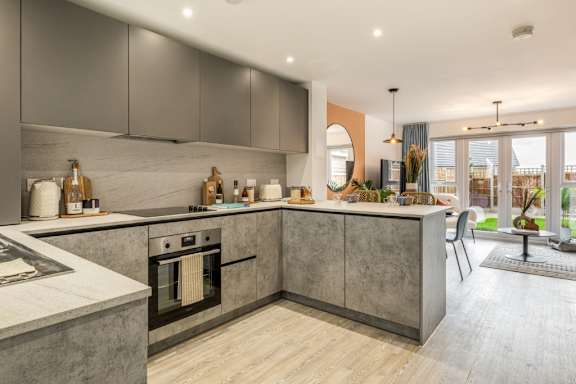 A modern kitchen with a marble countertop and wooden flooring.