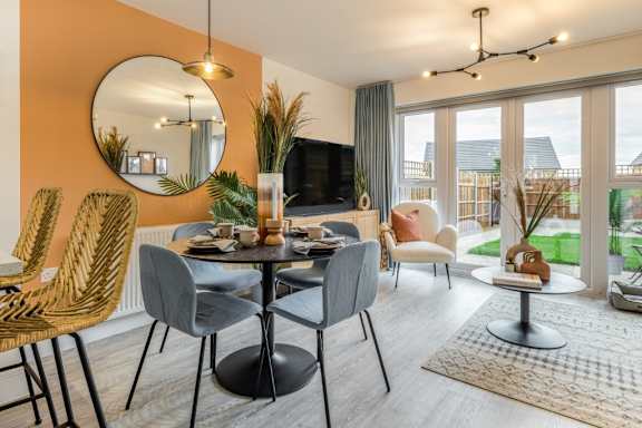 A modern dining room with a round mirror and a TV.