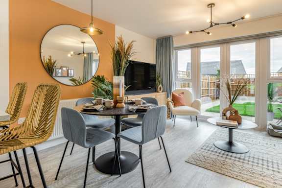 A modern dining room with a round mirror and a TV.