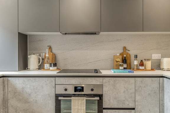 A modern kitchen with a stainless steel oven and grey cabinets.