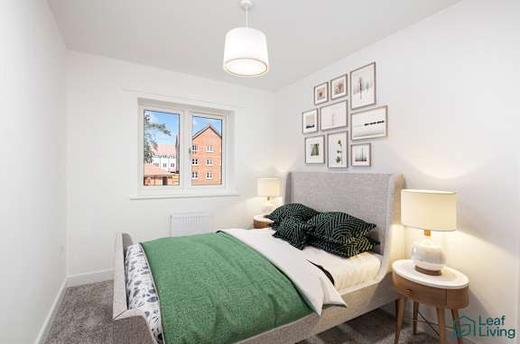 A bedroom with a bed, a nightstand, and pictures on the wall.