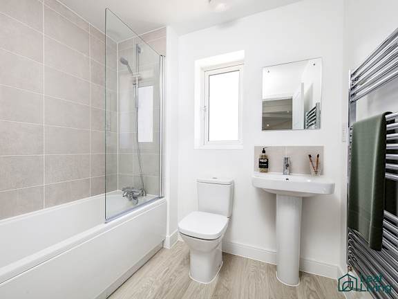 A white toilet sits next to a white sink in a bathroom.
