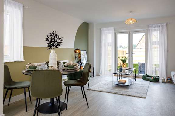 A dining room with a table set for four and a view of the backyard.