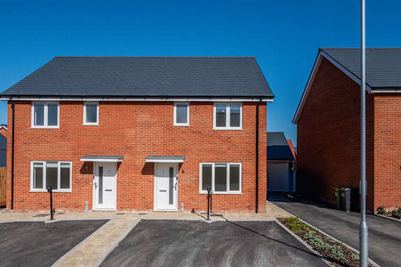 A red brick house with a black roof and white doors.